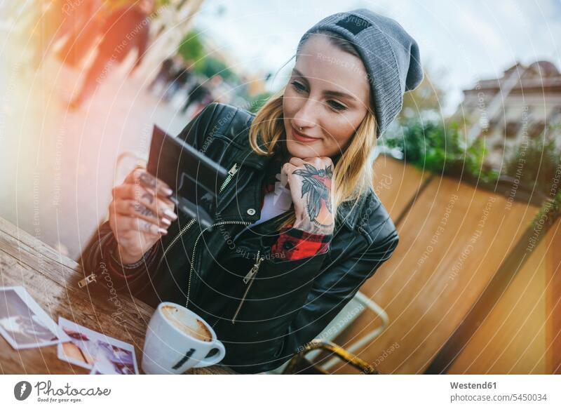 Young tattooed woman sitting in a pavement cafe looking at photos females women outdoor cafes portrait portraits Adults grown-ups grownups adult people persons