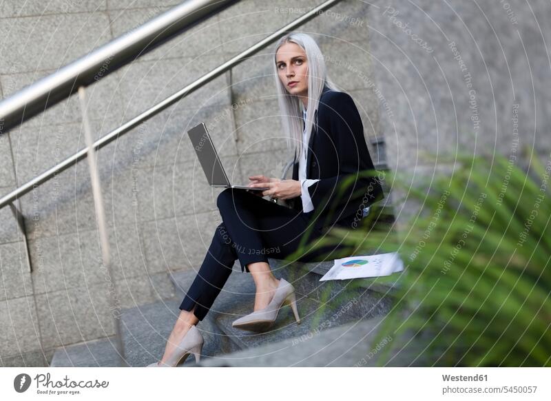 Young businesswoman sitting on stairs in the city using laptop Laptop Computers laptops notebook females women businesswomen business woman business women