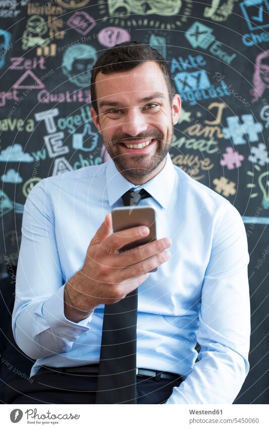 Portrait of smiling businessman with cell phone in creative office Businessman Business man Businessmen Business men smile mobile phone mobiles mobile phones