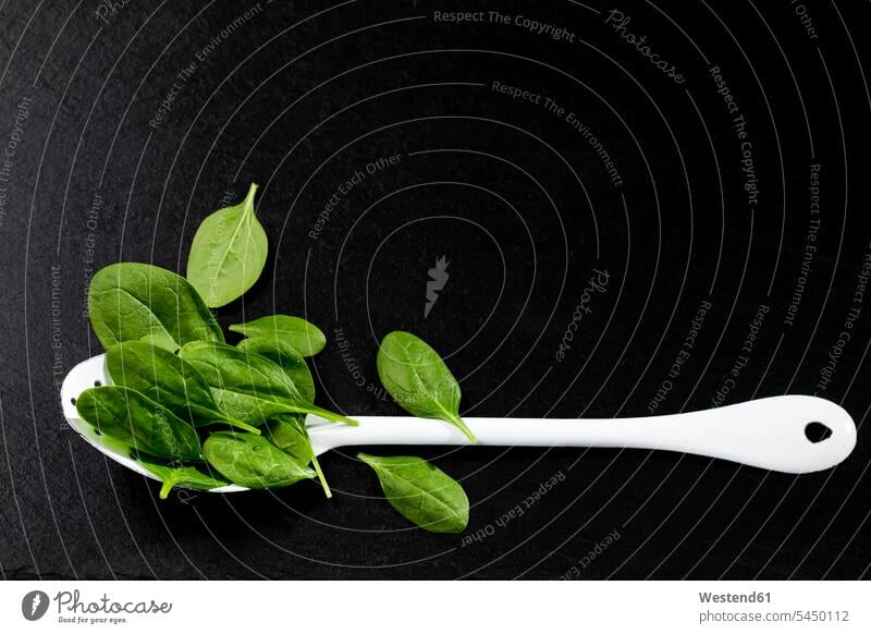 Leaf spinach and white spoon on slate green overhead view from above top view Overhead Overhead Shot View From Above schist slates copy space healthy eating
