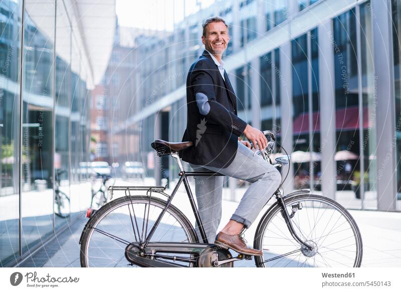 Smiling businessman on bicycle in the city smiling smile bikes bicycles Businessman Business man Businessmen Business men town cities towns transportation