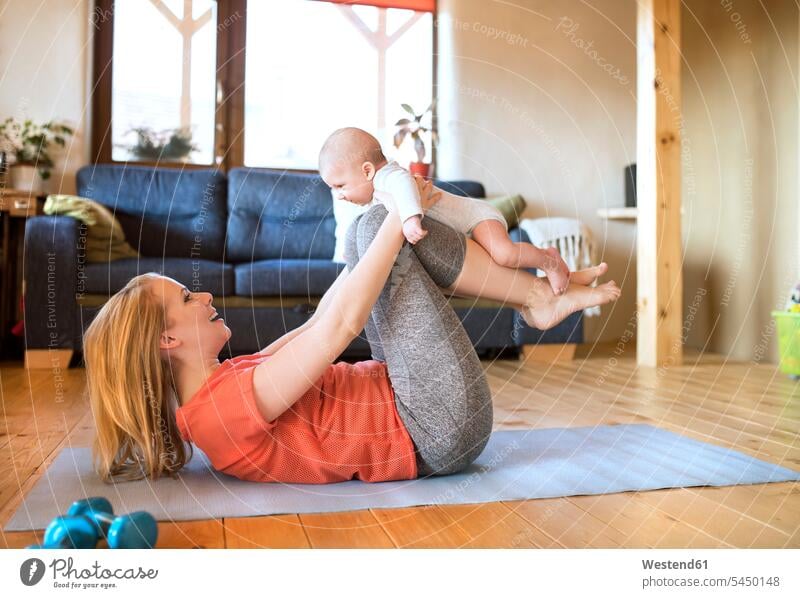 Happy mother lifting up baby at home lying on mat exercising exercise training practising smiling smile mommy mothers mummy mama Hand Weight Hand Weights