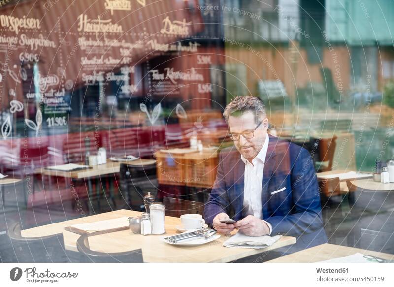 Mature businessman in cafe using cell phone Businessman Business man Businessmen Business men mobile phone mobiles mobile phones Cellphone cell phones