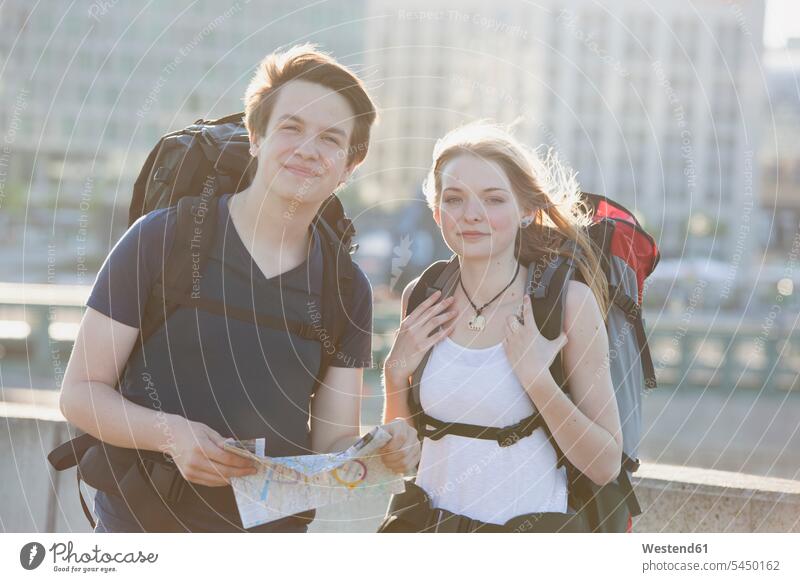 Germany, Berlin, Young couple traveling Berlin with backpacks, looking at map Traveller Travellers Travelers Sightseeing city map city maps visiting viewing