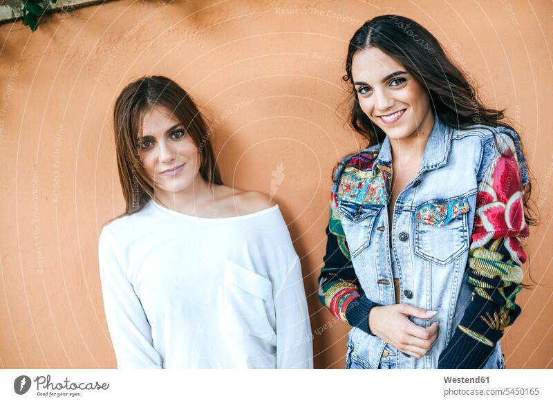 Portrait of two friends leaning against wall female friends walls portrait portraits mate friendship relationship Human Relationship fashionable tilted slanted