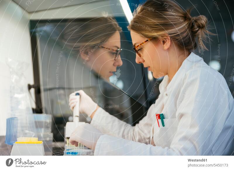 Laboratory technician pipetting in lab laboratory woman females women examining checking examine working At Work laboratory technician workplace work place