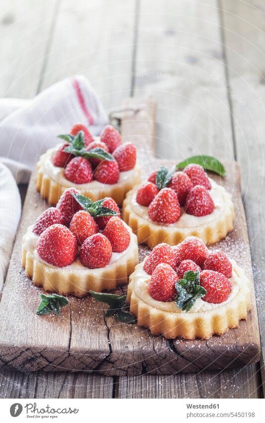 Tartlets with pudding filling and strawberries sweet Sugary sweets icing sugar powdered sugar garnished ready to eat ready-to-eat wooden board wooden boards