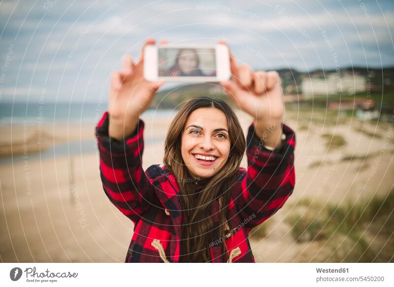 Portrait of smiling woman taking selfie with smartphone on the beach beaches Selfie Selfies females women portrait portraits Adults grown-ups grownups adult