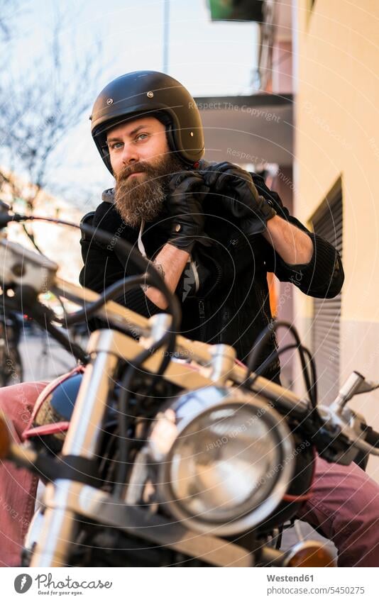 Portrait of bearded biker fastening helmet while sitting on his motorcycle motorbike Motor Cycle motorcyclist motor vehicle road vehicle road vehicles