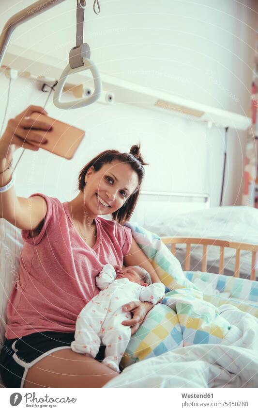Mother taking a selfie with her newborn baby in hospital bed Selfie Selfies mother mommy mothers ma mummy mama parents family families people persons