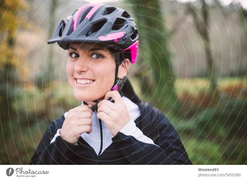 Portrait of smiling woman putting on bicycle helmet mountain biking MTB mountainbiking smile cycling helmet Bike Helmet bicycle helmets cycling helmets