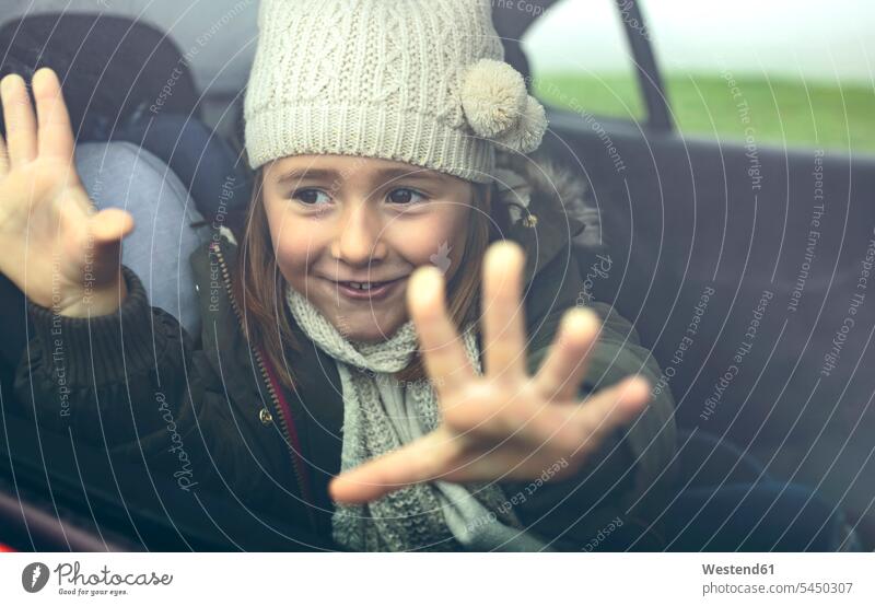 Portrait of happy little girl with wool cap putting her fingers on car window smiling smile females girls hand human hand hands human hands automobile Auto cars