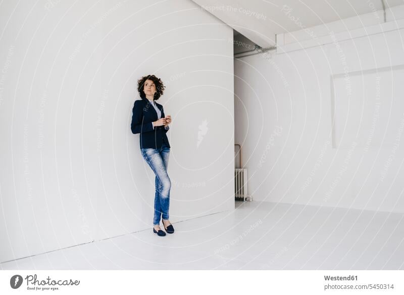 Businesswoman standing in loft , leaning against wall curly hair curls thinking businesswoman businesswomen business woman business women people persons