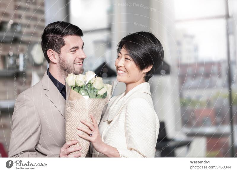 Man handing over roses to woman at home smiling smile Rose Roses Rosa couple twosomes partnership couples Bunch of Flowers Bouquet Flower Bouquet
