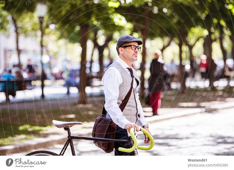 Mature businessman on bicycle in the city bikes bicycles men males town cities towns Adults grown-ups grownups adult people persons human being humans