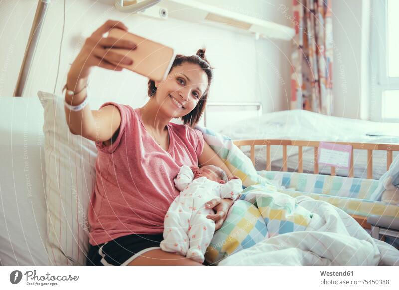 Mother taking a selfie with her newborn baby in hospital bed mother mommy mothers ma mummy mama Selfie Selfies parents family families people persons