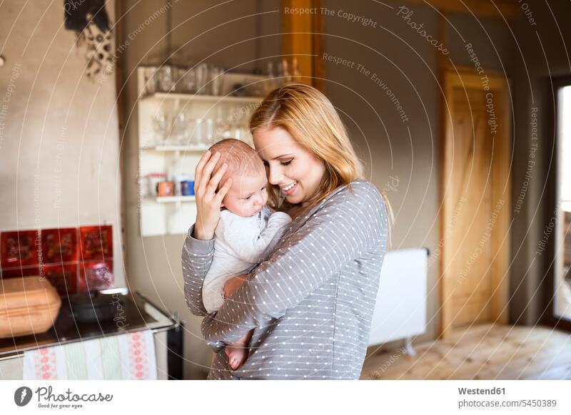 Smiling mother holding baby at home infants nurselings babies smiling smile mommy mothers ma mummy mama people persons human being humans human beings parents