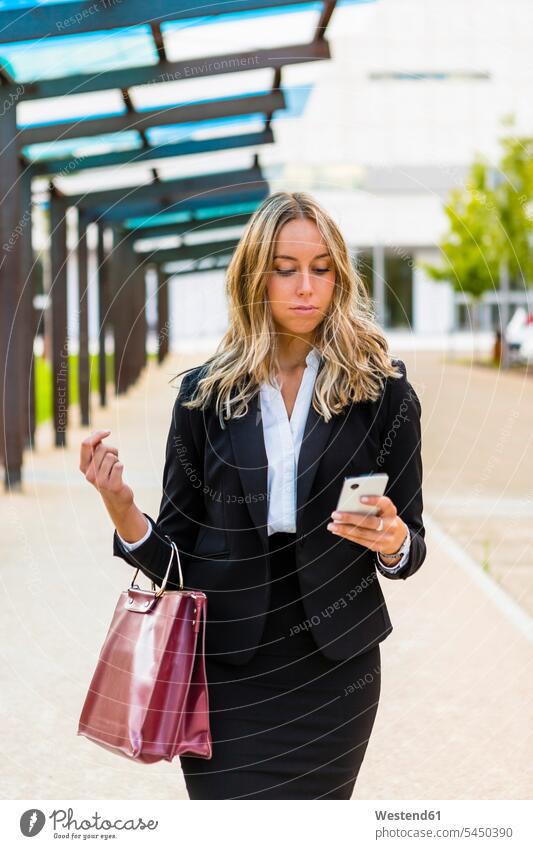 Businesswoman with fashionable leatherbag looking at cell phone businesswoman businesswomen business woman business women briefcase brief case business people