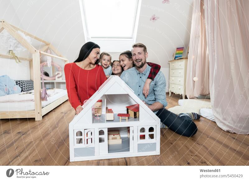 Happy family with three daughters sitting behind doll house in nursery Fun having fun funny laughing Laughter families children's room Kids Room child's room