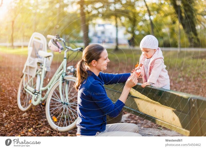Mother and daughter taking a break on a park bench park benches standing bicycle bikes bicycles riding bicycle riding bike bike riding cycling bicycling