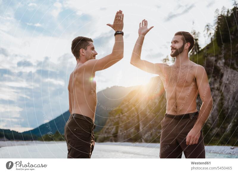 Germany, Bavaria, two best friends high fiving in nature High Five Hi-Five high-fiving High-Five friendship sunset sunsets sundown shirtless bare chest