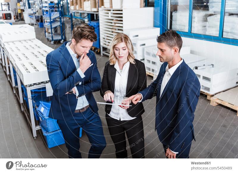 Three business people discussing on shop floor, using digital tablet Business Meeting business conference meeting businesspeople Meetings discussion standing