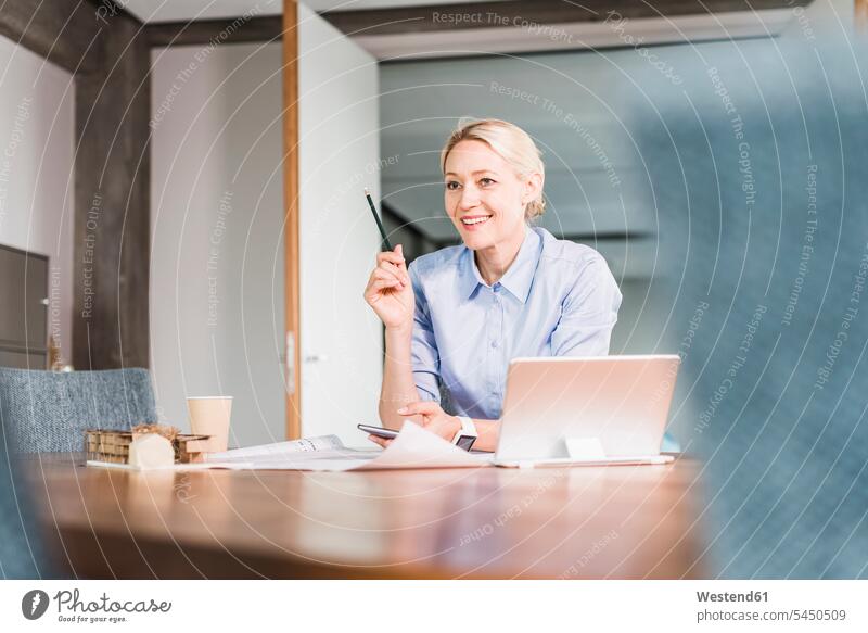 Smiling businesswoman working at desk in office smiling smile businesswomen business woman business women At Work business people businesspeople business world