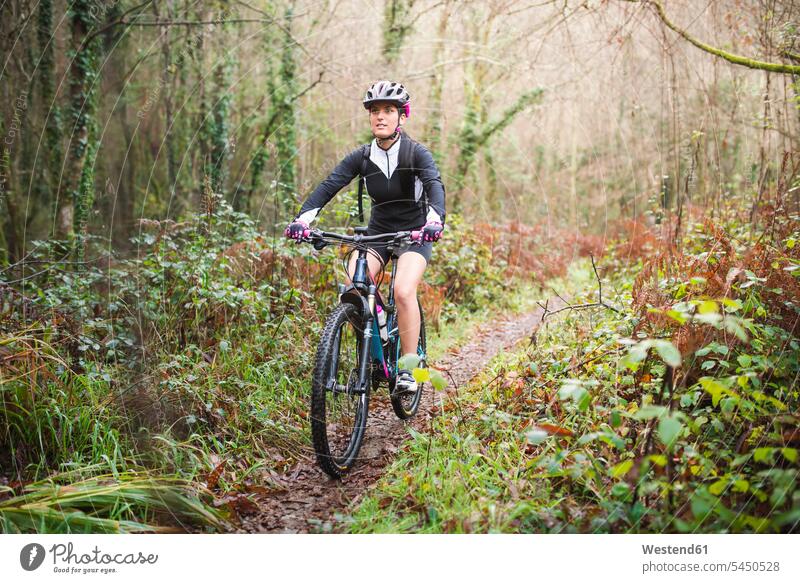 Female mountain biker riding her bike on a trail in forest mountain biking MTB mountainbiking woman females women cycling sport sports bicycle bikes bicycles
