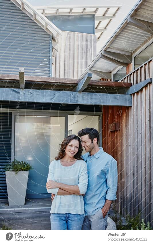 Couple standing in front of door of their home together home ownership private owned home couple twosomes partnership couples happiness happy entrance entry
