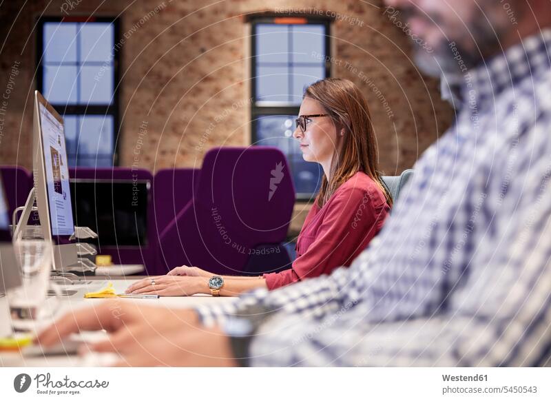 Woman working focused on PC Female Colleague business people businesspeople sitting Seated At Work office offices office room office rooms colleagues