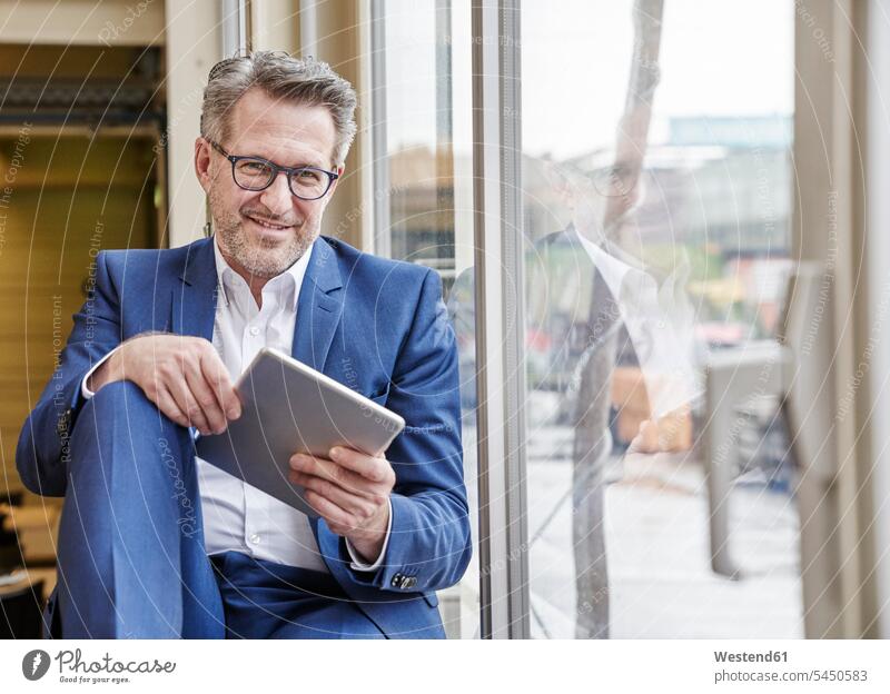 Smiling mature businessman using tablet at the window Businessman Business man Businessmen Business men smiling smile digitizer Tablet Computer Tablet PC