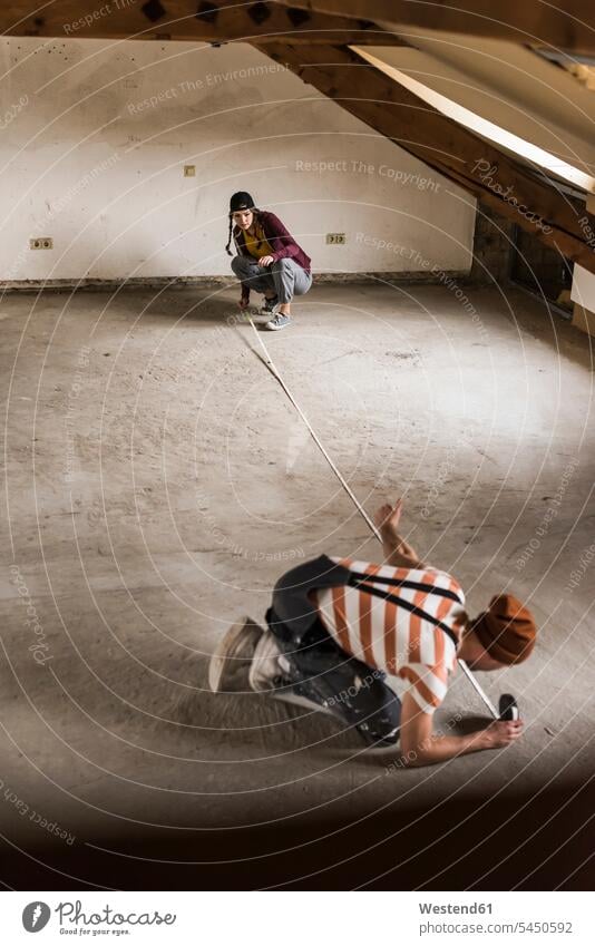 Young man and woman measuring floor on construction site couple twosomes partnership couples DIY Doityourself Do it yourself Do-it-yourself measure measurement