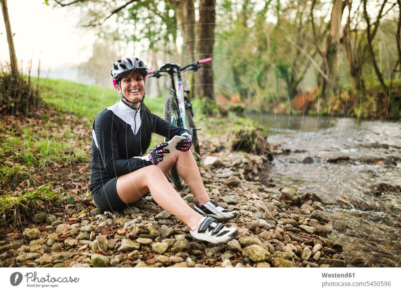Happy woman with mountain bike and cell phone resting in nature females women laughing Laughter mountain biking MTB mountainbiking mobile phone mobiles