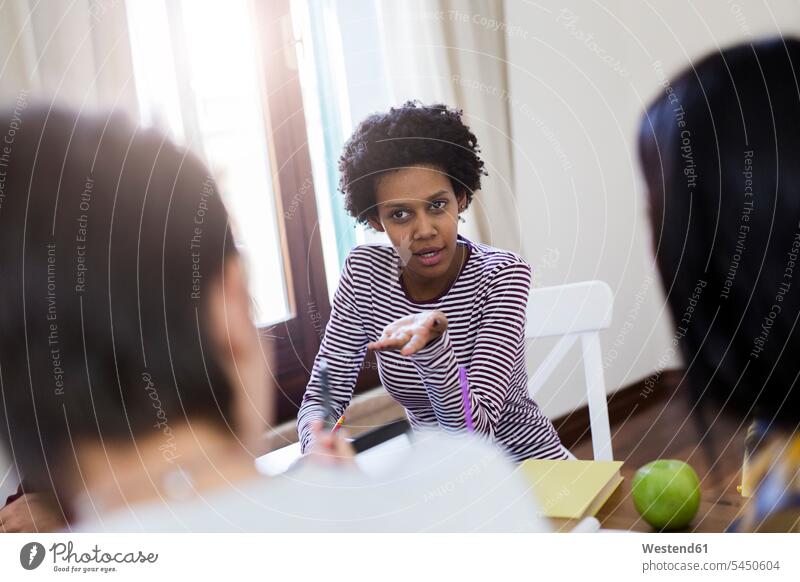 Group of female students discussing at table at home Table Tables teamwork teamworking talking speaking woman females women discussion education Adults