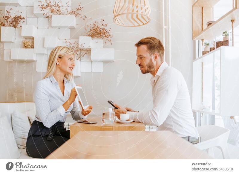 Businessman and businesswoman having a meeting in a cafe businesswomen business woman business women tablet digitizer Tablet Computer Tablet PC Tablet Computers