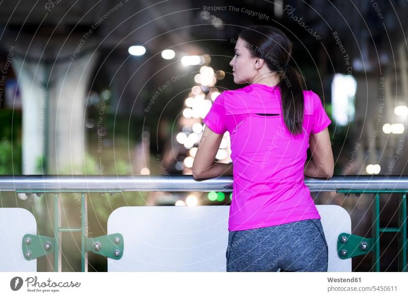 Young woman in pink sportshirt watching urban city lights at night young women young woman exercising exercise training practising jogger joggers female jogger