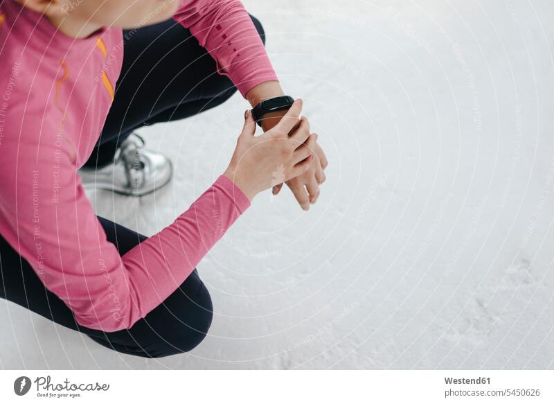 Woman in sportswear crouching wearing activity band fitness tracker activity tracker woman females women cowering Sportswear Activewear Sport Clothes