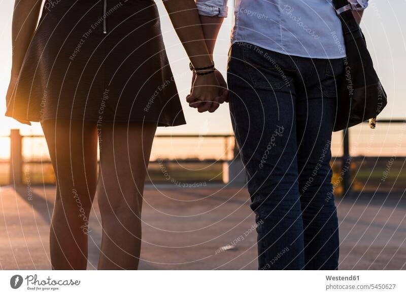 Young couple hand in hand on parking level at sunset sunsets sundown twosomes partnership couples atmosphere atmospheric mood moody Atmospheric Mood Vibe