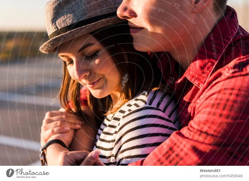Close-up of young couple hugging at sunset sunsets sundown embracing embrace Embracement twosomes partnership couples atmosphere atmospheric mood moody