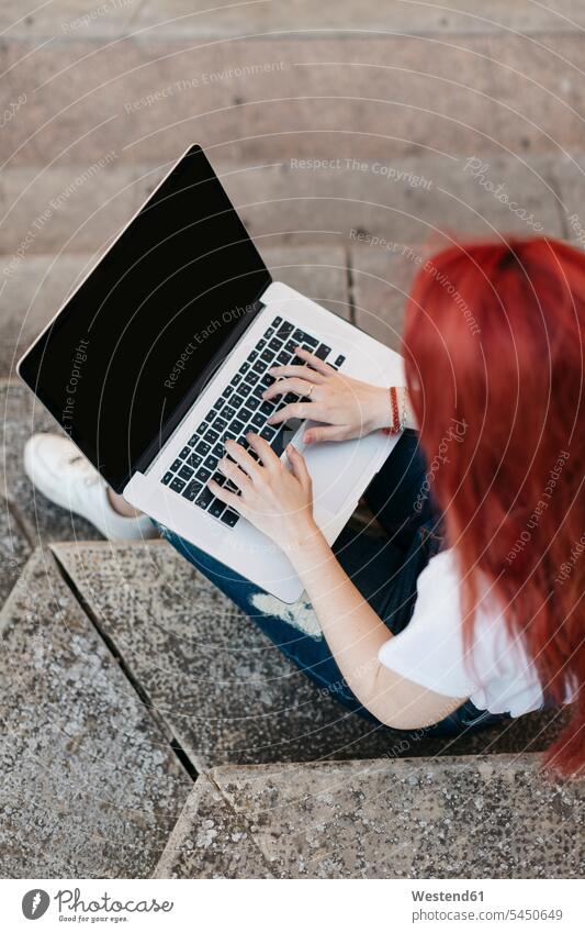 Redheaded woman sitting on stairs using laptop, top view Laptop Computers laptops notebook females women computer computers Adults grown-ups grownups adult