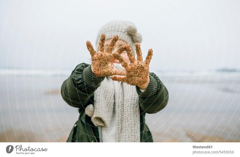 Girl showing her sandy hands on the beach in winter playing beaches human hand human hands girl females girls people persons human being humans human beings
