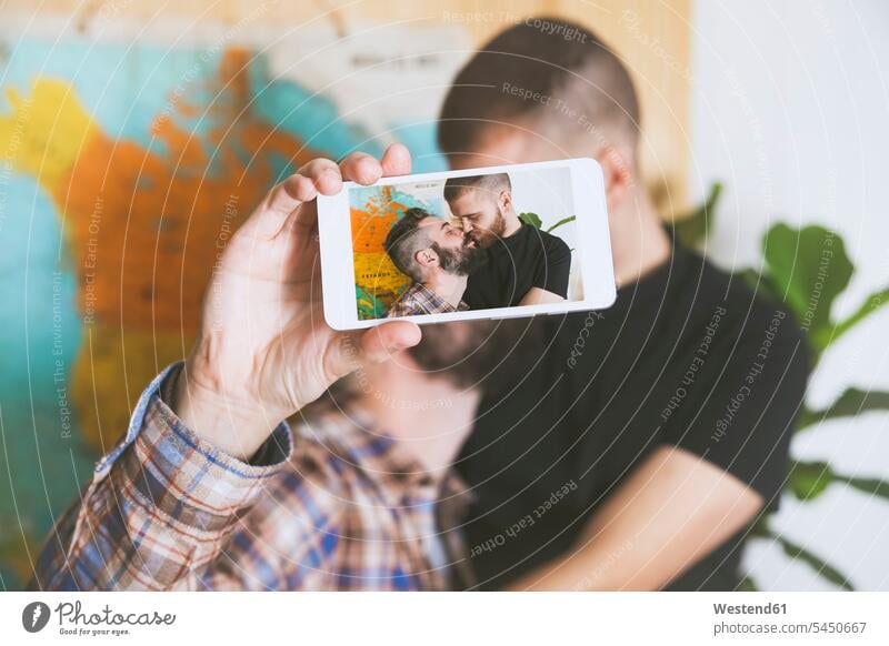 Young gay couple taking a selfie with smartphone, close-up twosomes partnership couples gay men gay man homosexual men homosexual man Selfie Selfies queer