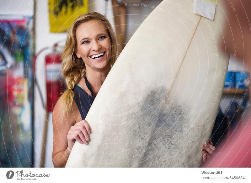 Surfboard shaper workshop, female employee smiling with surfboard laughing Laughter surfboards woman females women positive Emotion Feeling Feelings Sentiments