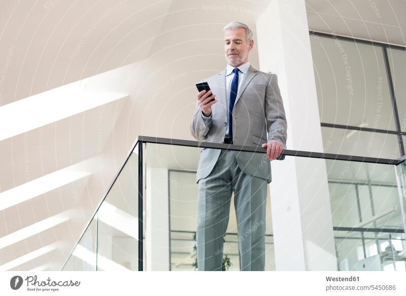 Businessman standing in office using his mobile phone Business man Businessmen Business men reading Success successful text messaging SMS Text Message offices