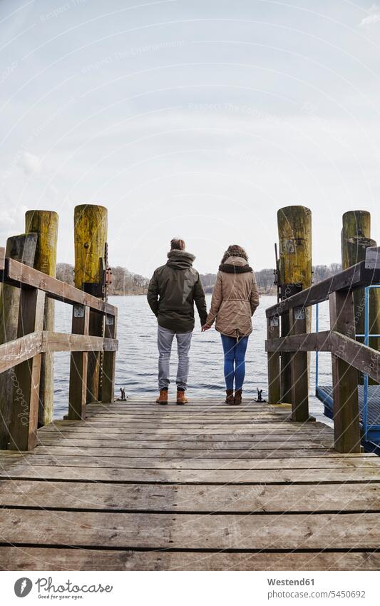 Germany, Potsdam, rear view of young couple standing on jetty at Havel River lake lakes looking seeing viewing twosomes partnership couples jetties water waters