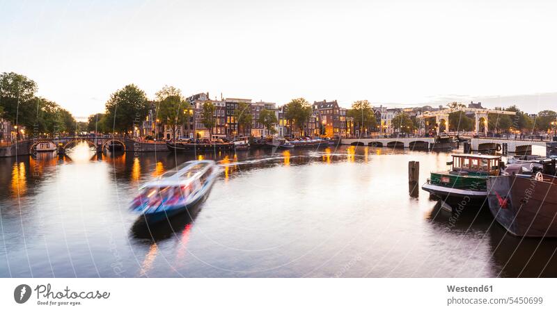Netherlands, Amsterdam, view to the old town and Magere Brug with Amstel River in the foreground nobody evening in the evening historical tourboat