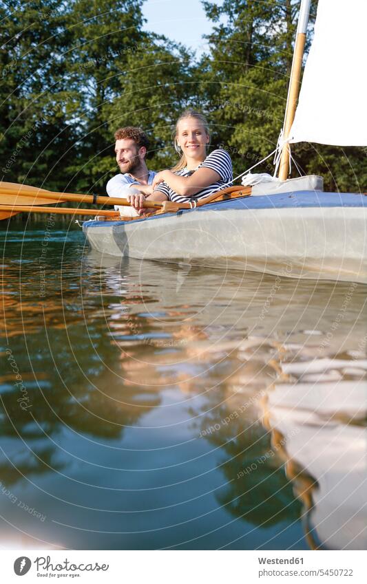 Young couple enjoying a trip in a canoe with sail on a lake indulgence enjoyment savoring indulging lakes twosomes partnership couples excursion Getaway Trip