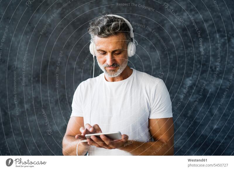 Portrait of a mature man using smartphone, wearing headphones mature men music Smartphone iPhone Smartphones call telephone call Phone Call on the phone