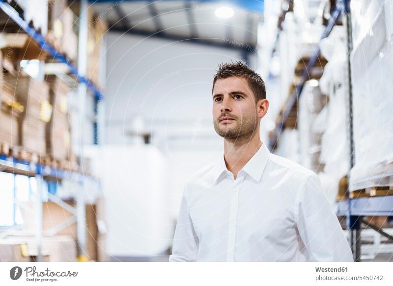 Businessman standing in warehouse, portrait employee clerk employees clerks Business man Businessmen Business men product products confidence confident factory