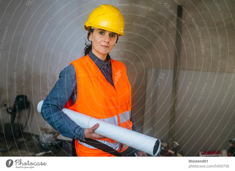 Woman wearing hard hat and reflective vest on construction site holding blueprint Building Site sites Building Sites construction sites working At Work woman